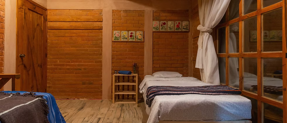 A simple guest room with two beds and brick walls