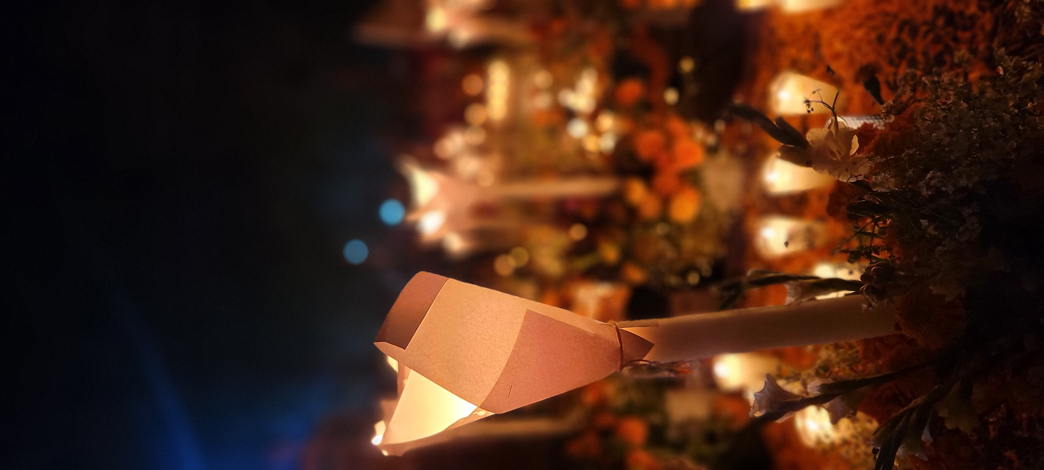A paper lantern lit on a candle stem among marigolds
