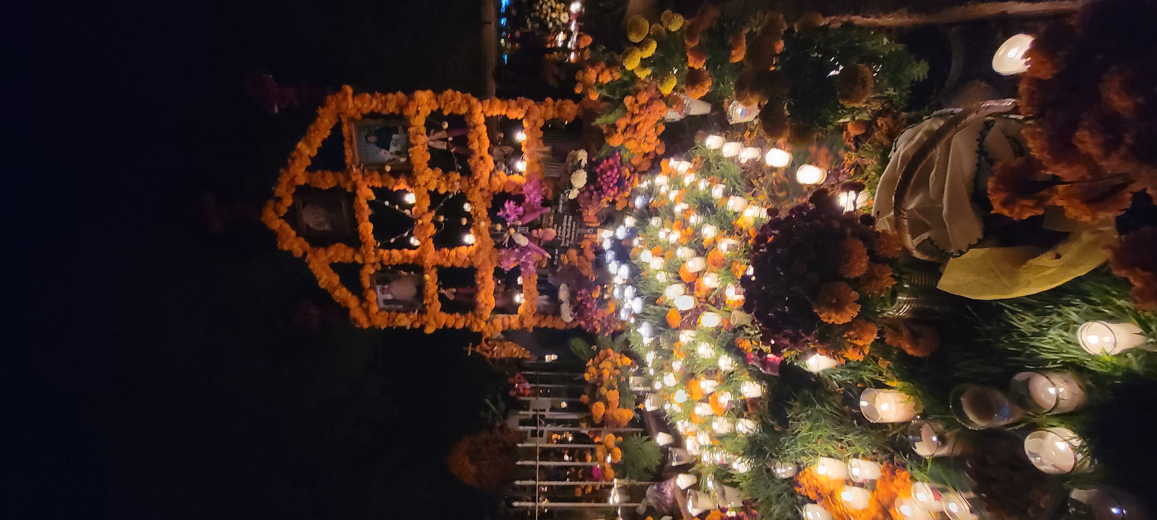 A marigold ofrenda lit with candles at night